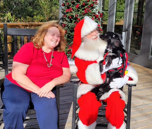 Santa Truette holding a black dog beside its owner