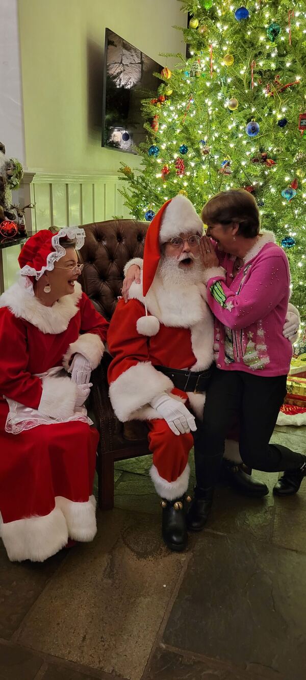 Guest with Santa and Mrs. Claus beside a Christmas tree