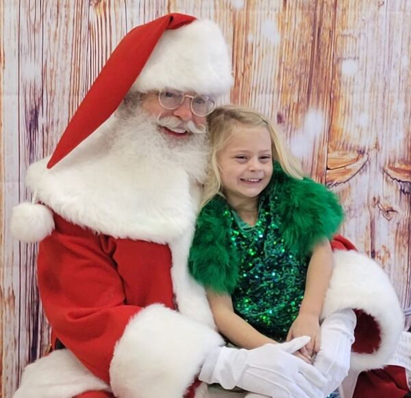 Girl in a green sequin dress on Santa's lap