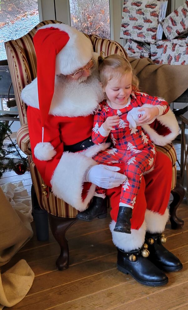 Toddler in Christmas pajamas on Santa's lap