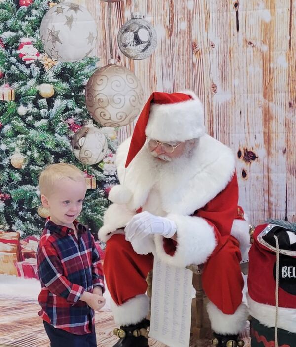Toddler in a plaid shirt meeting Santa Truette