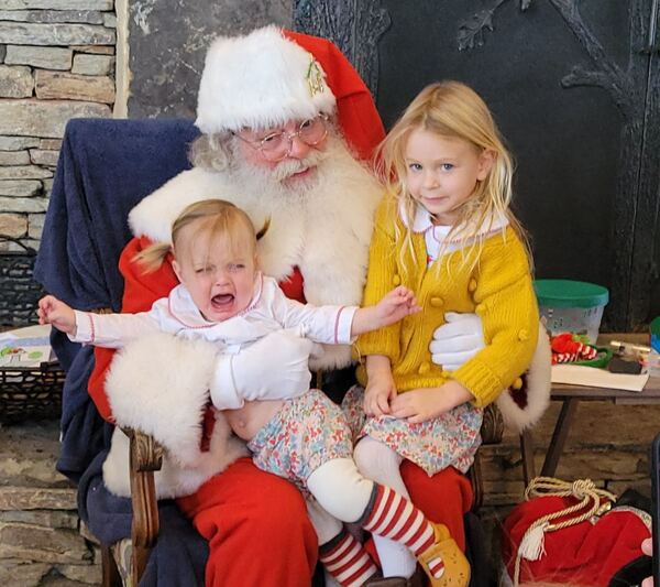 Crying baby and big sister on Santa's lap