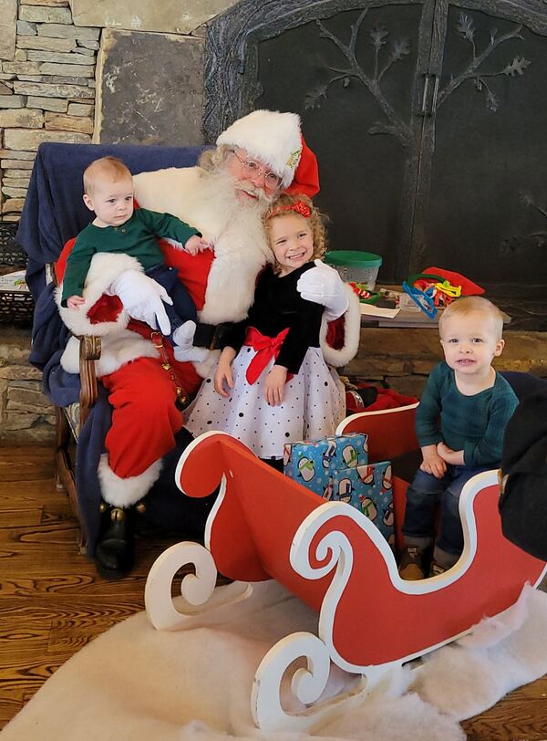 Children riding in a red sleigh with Santa Truette