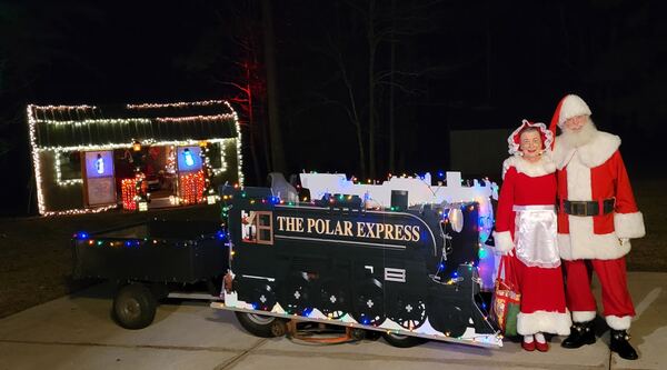 Santa and Mrs. Claus beside the Polar Express train at night
