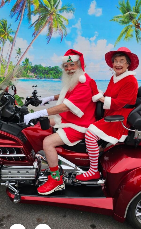Santa and Mrs. Claus on a red motorcycle in a tropical set