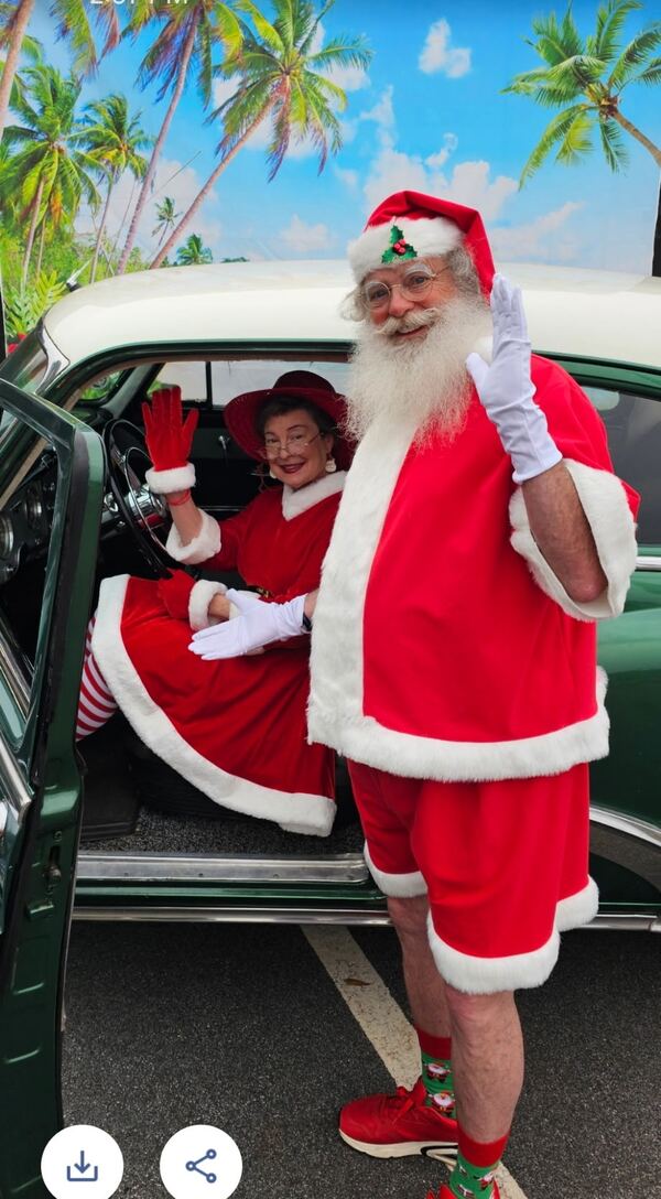 Santa Truette and Mrs. Claus in a vintage car with a tropical backdrop