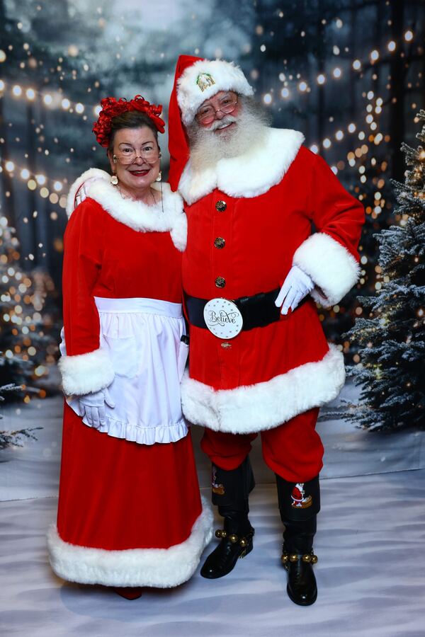 Santa Truette and Mrs. Claus Nancy standing together in a snowy forest