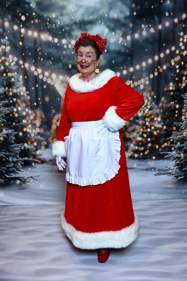 Mrs. Claus Nancy in her full red dress and apron in the snow