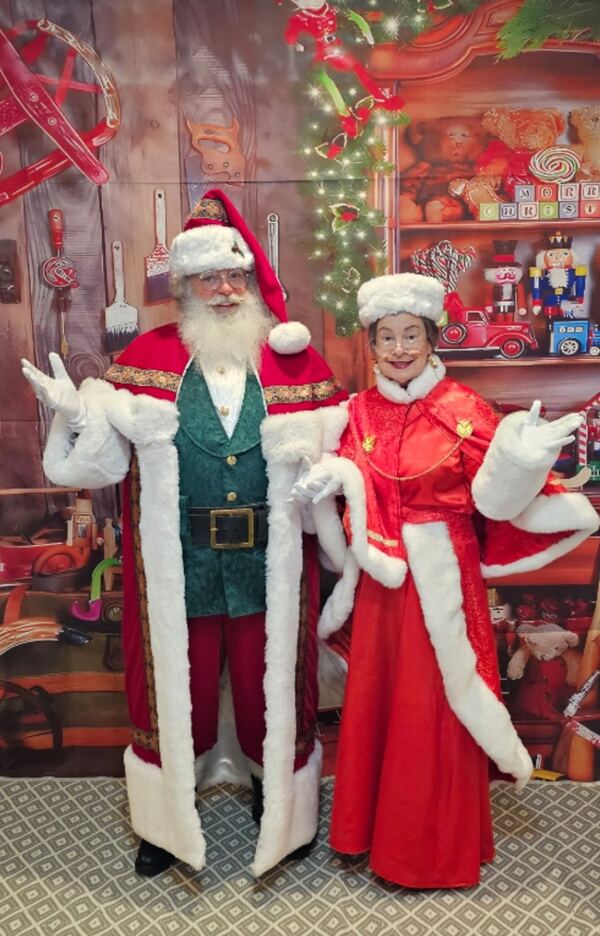 Santa Truette and Mrs. Claus Nancy waving in a toy-shop set