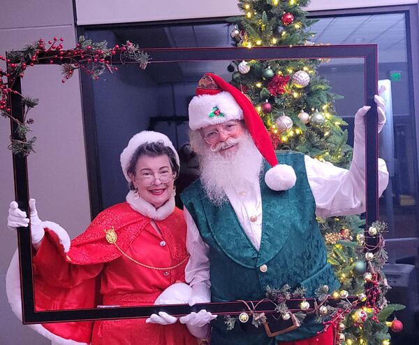 Mrs. Claus Nancy and Santa Truette posing with a Christmas picture frame