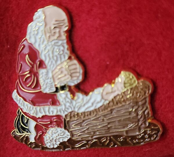 Enamel pin of Santa kneeling at the manger