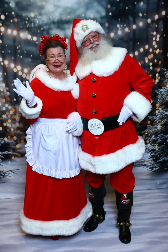 Santa Truette and Mrs. Claus Nancy waving in a snowy forest